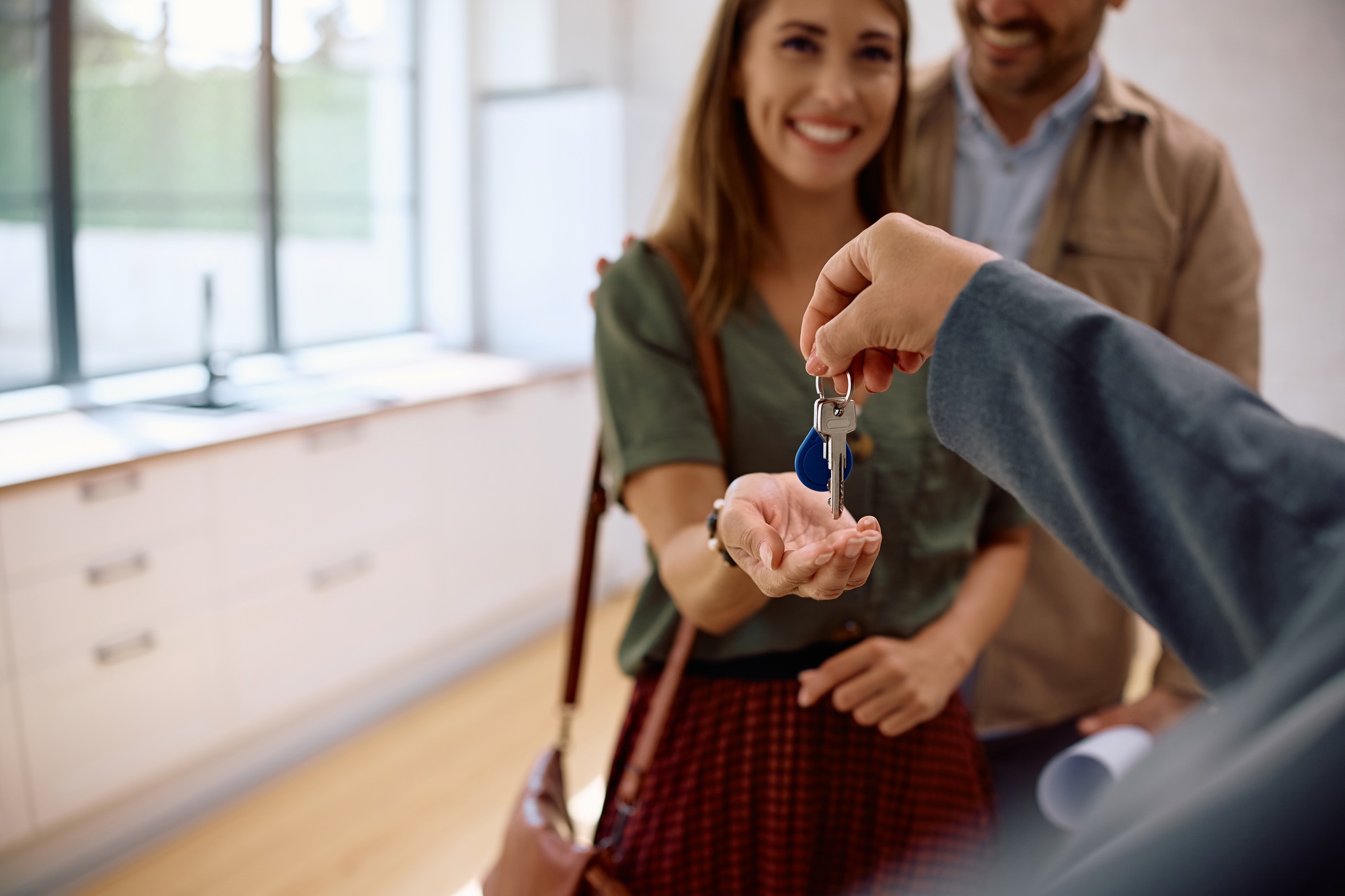 Close up of couple receiving keys of their new home from real estate agent.